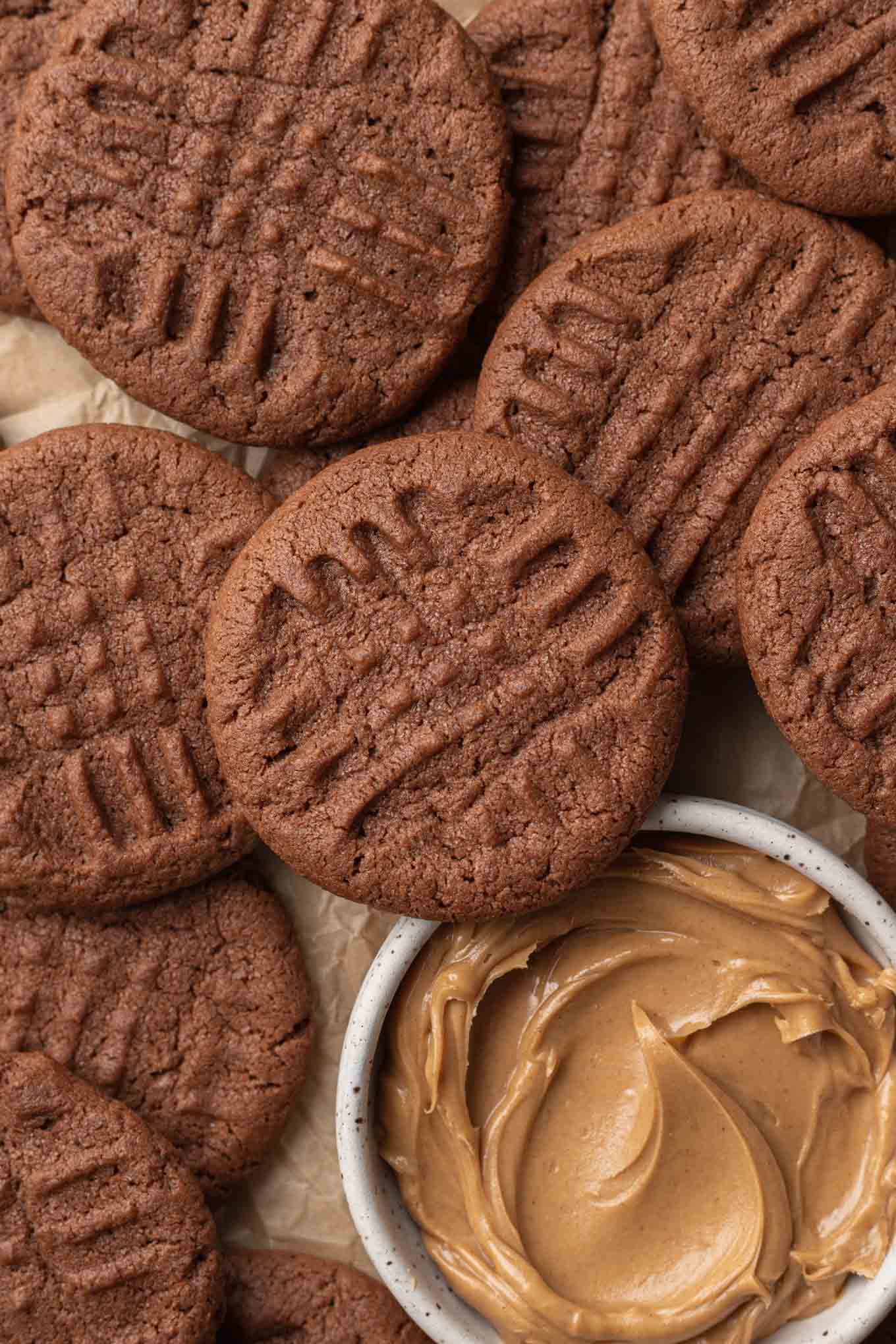 Una vista aérea en primer plano de galletas de chocolate y mantequilla de maní, con un plato de mantequilla de maní. 