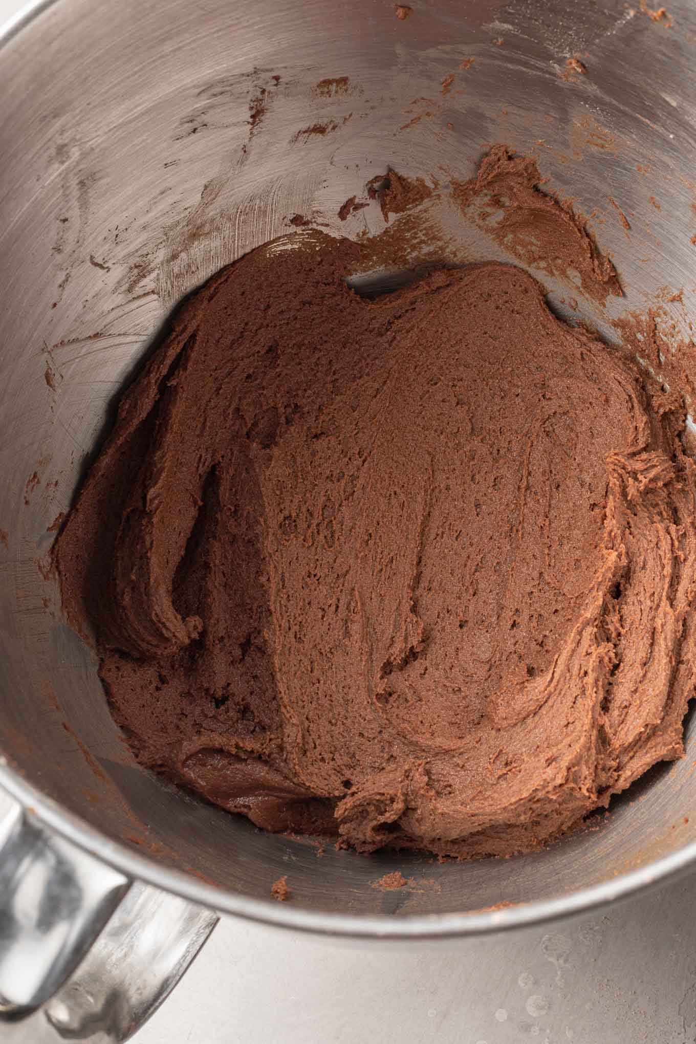 Una vista aérea de la masa de galleta de chocolate y menta en el tazón de una batidora de pie. 