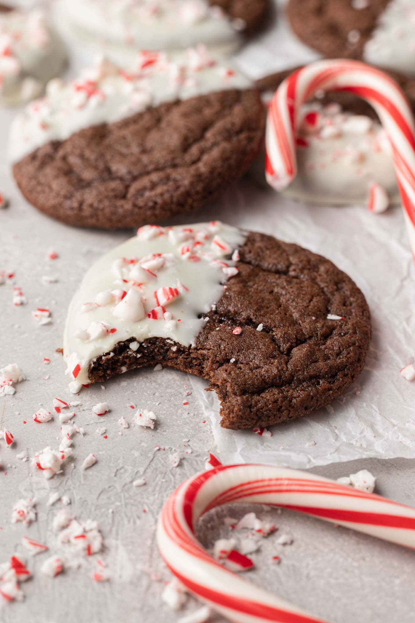 Una galleta navideña de chocolate y menta a la que le falta un bocado, rodeada de galletas adicionales. 