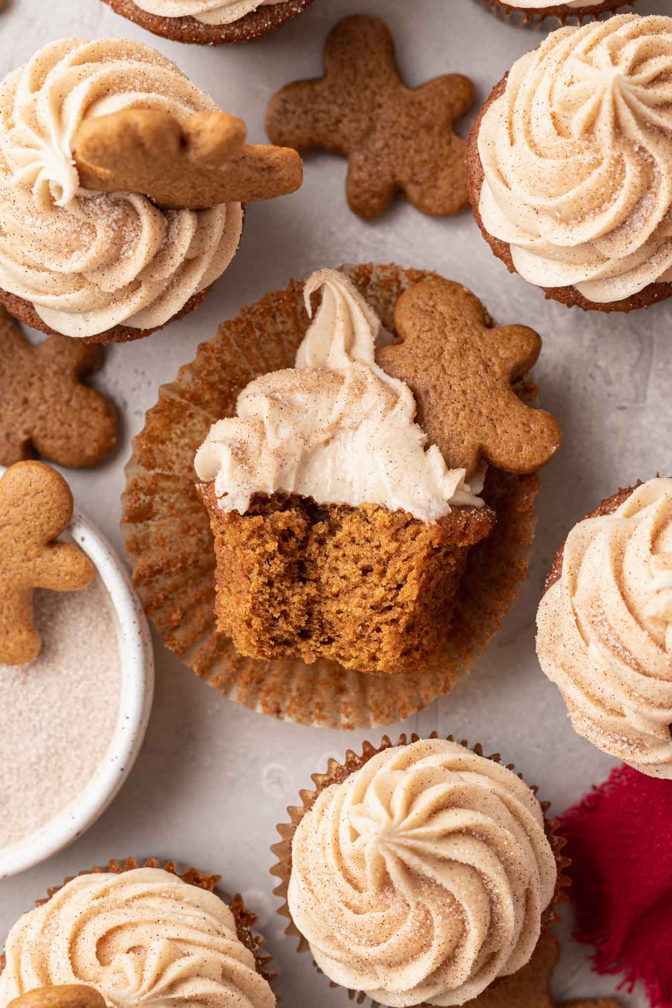 Una vista aérea de un cupcake de pan de jengibre de lado en un molde para cupcakes, al que le falta un bocado. 