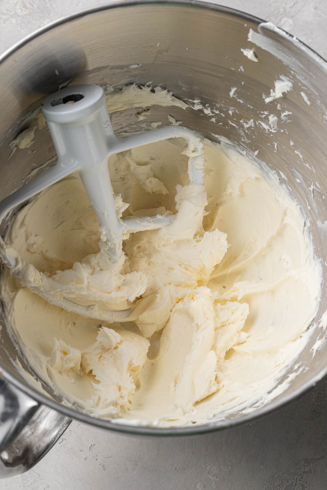 Una vista aérea del queso crema y la mantequilla en el tazón de una batidora. 