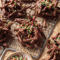 Varias galletas de paja cubiertas con chispas rojas y verdes sobre una pequeña rejilla.