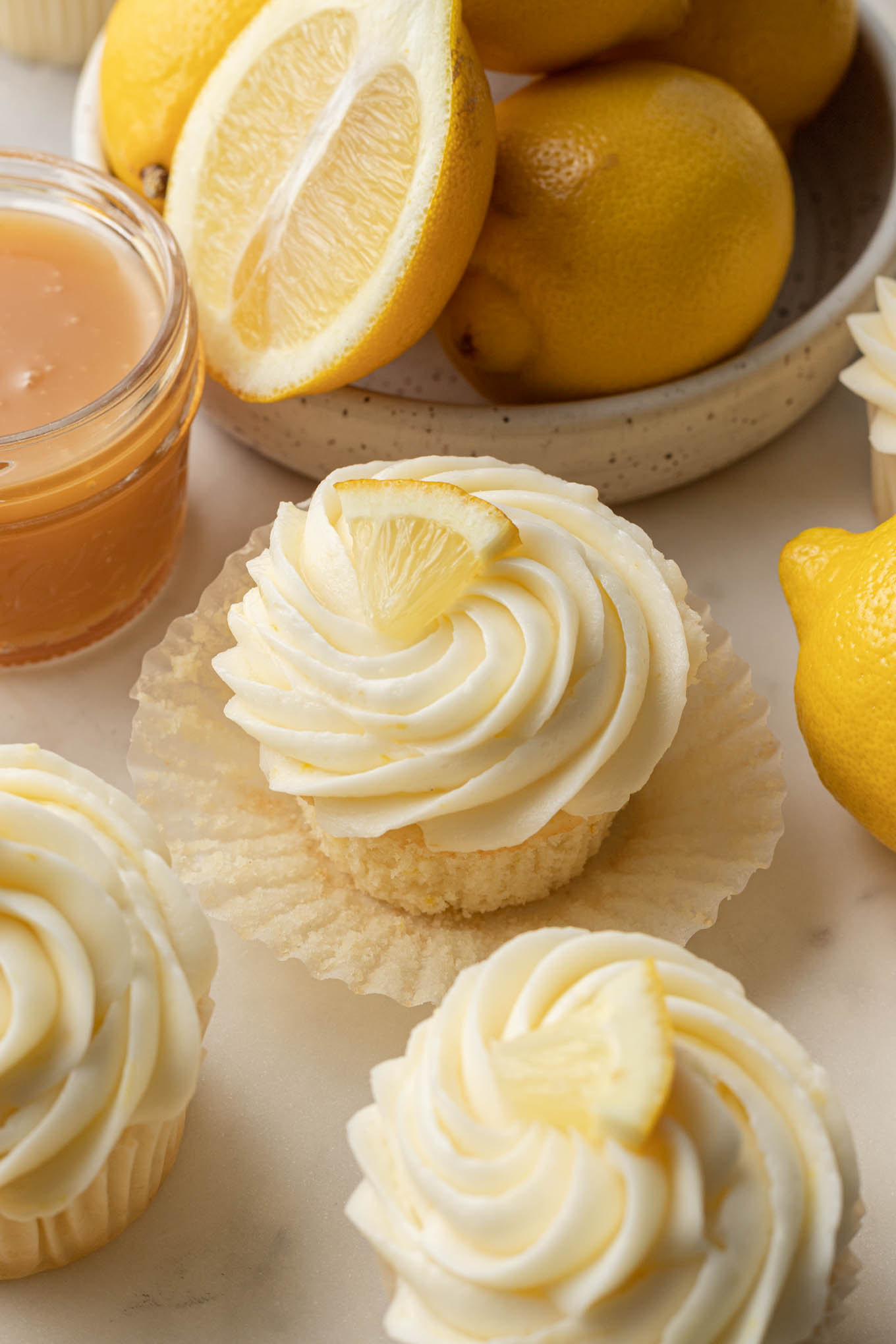 Cupcakes de limón en moldes para cupcakes, rodeados de limones frescos.
