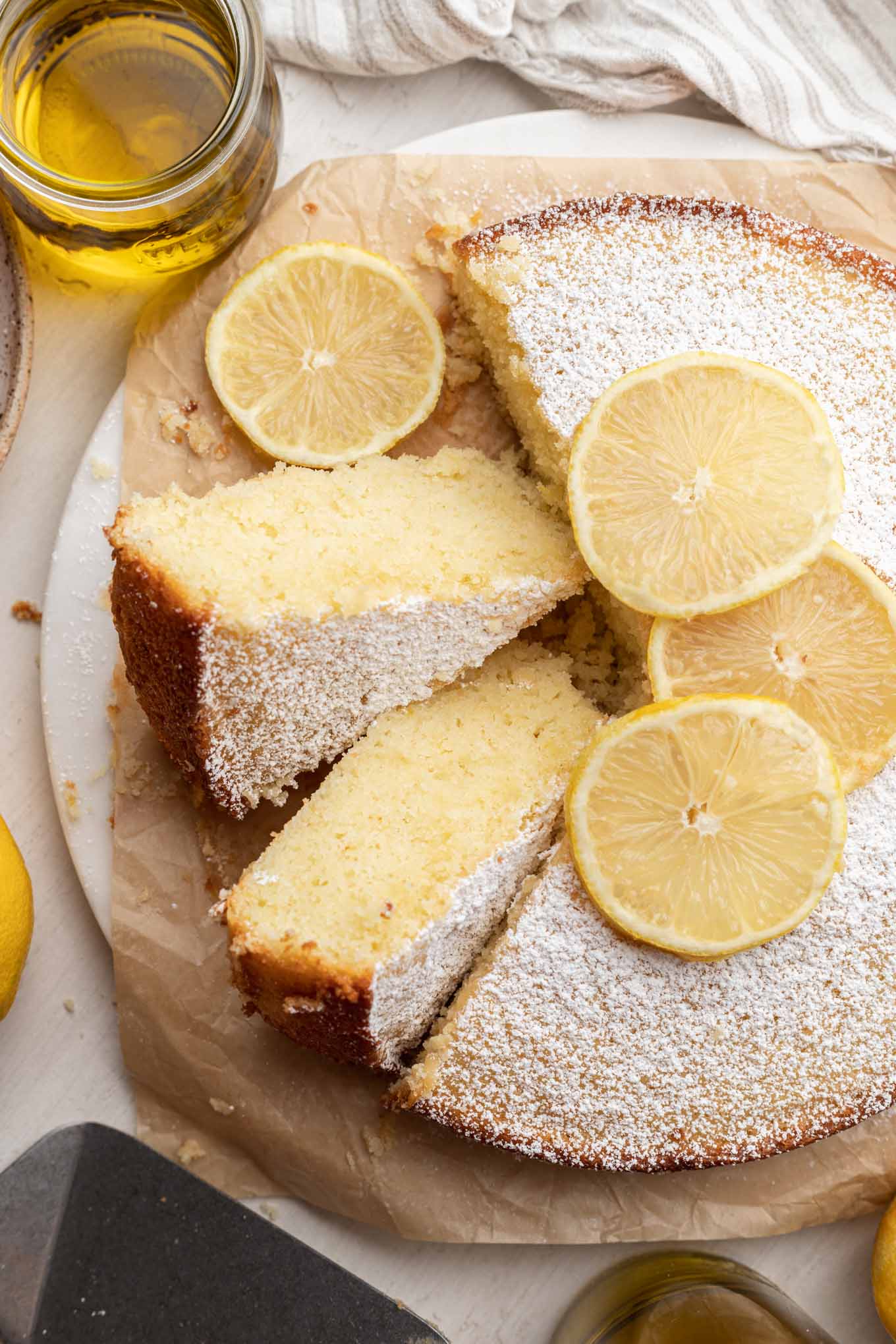 Una vista aérea de un pastel de limón y aceite de oliva, con dos rebanadas volteadas de lado. 