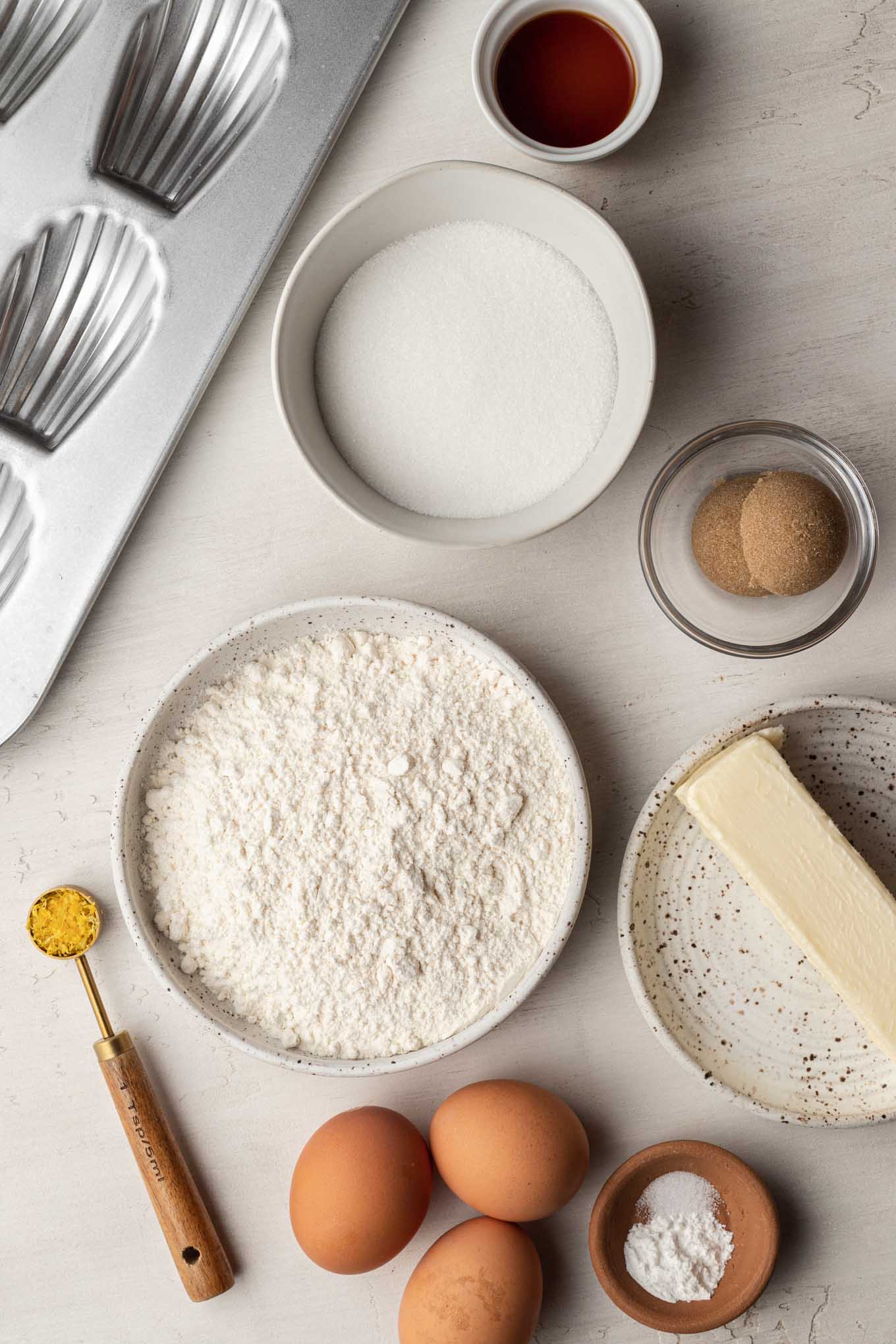 Una vista aérea de los ingredientes necesarios para hacer galletas magdalenas francesas. 