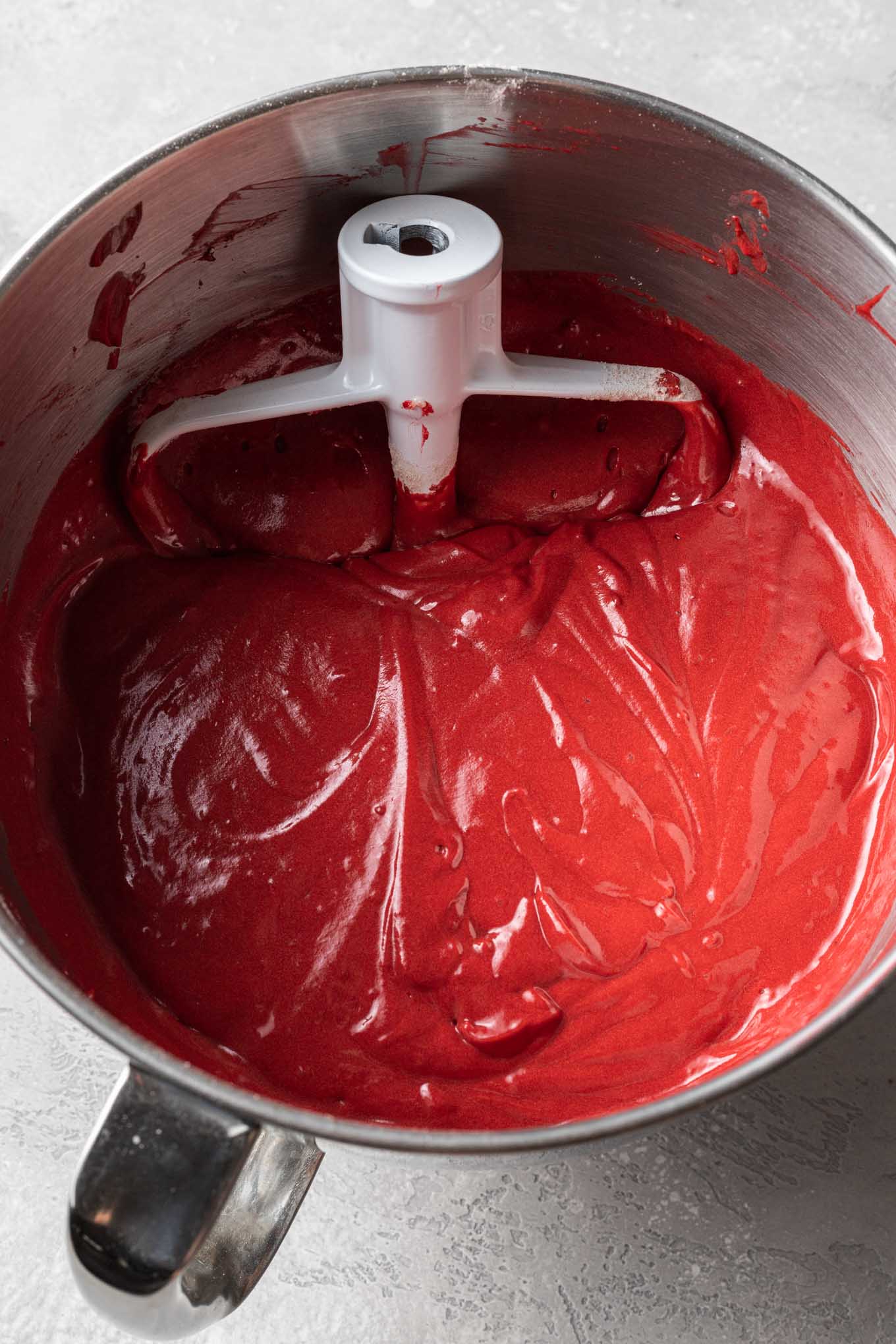 Una vista dall'alto della pastella per torta Red Velvet in una ciotola con attacco a paletta.