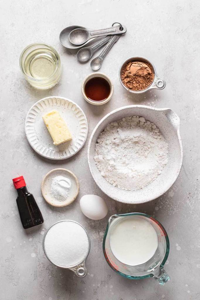 Una vista aérea de los ingredientes necesarios para hacer cupcakes de terciopelo rojo con glaseado de queso crema. 