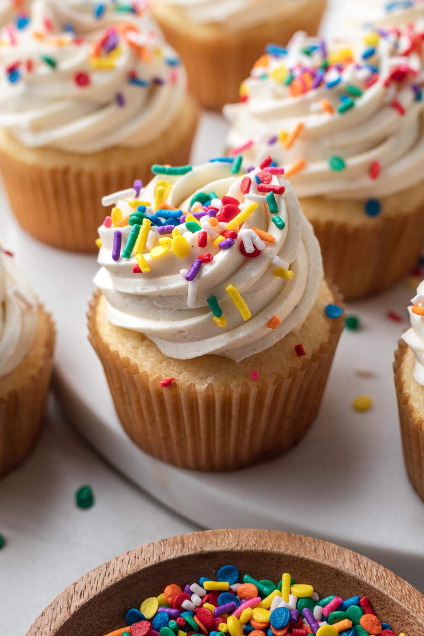 Cupcakes caseros de vainilla cubiertos con glaseado y chispas. 