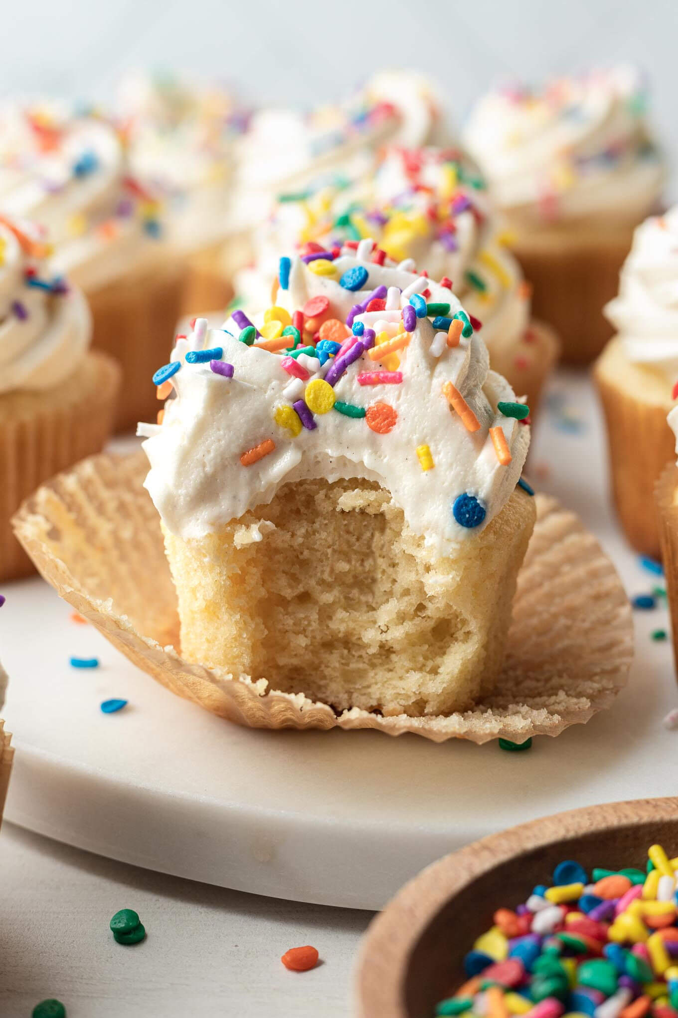 Una vista lateral de un cupcake al que le falta un bocado y el forro del cupcake bajado. 