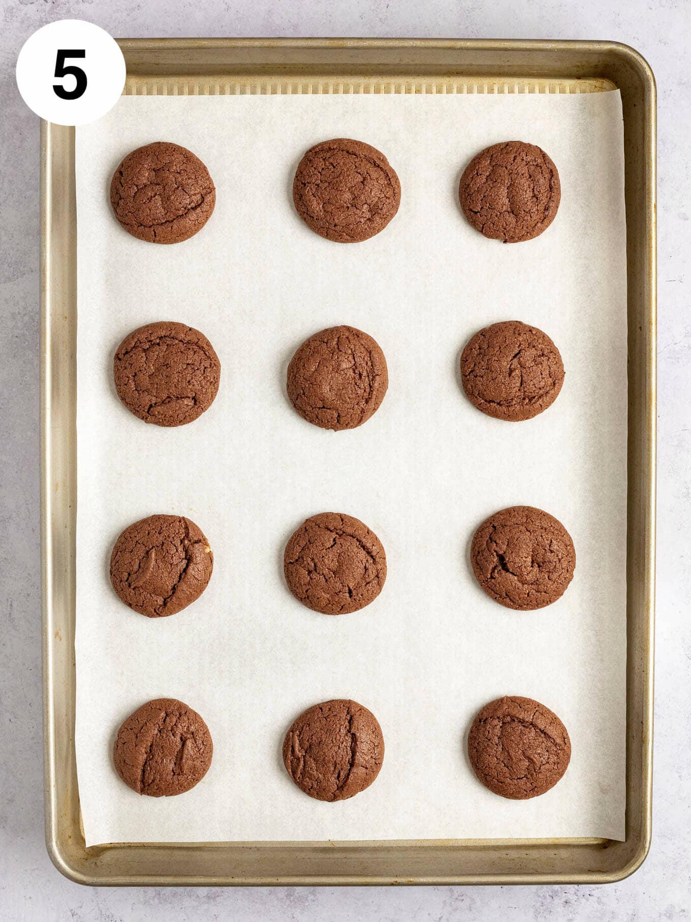 Una vista aérea de galletas de chocolate horneadas en una bandeja para hornear forrada con papel pergamino.