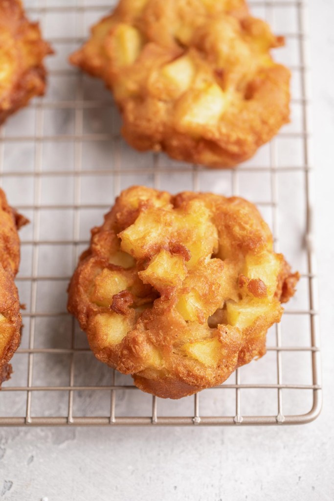 Buñuelos de manzana caseros enfriándose sobre una rejilla.