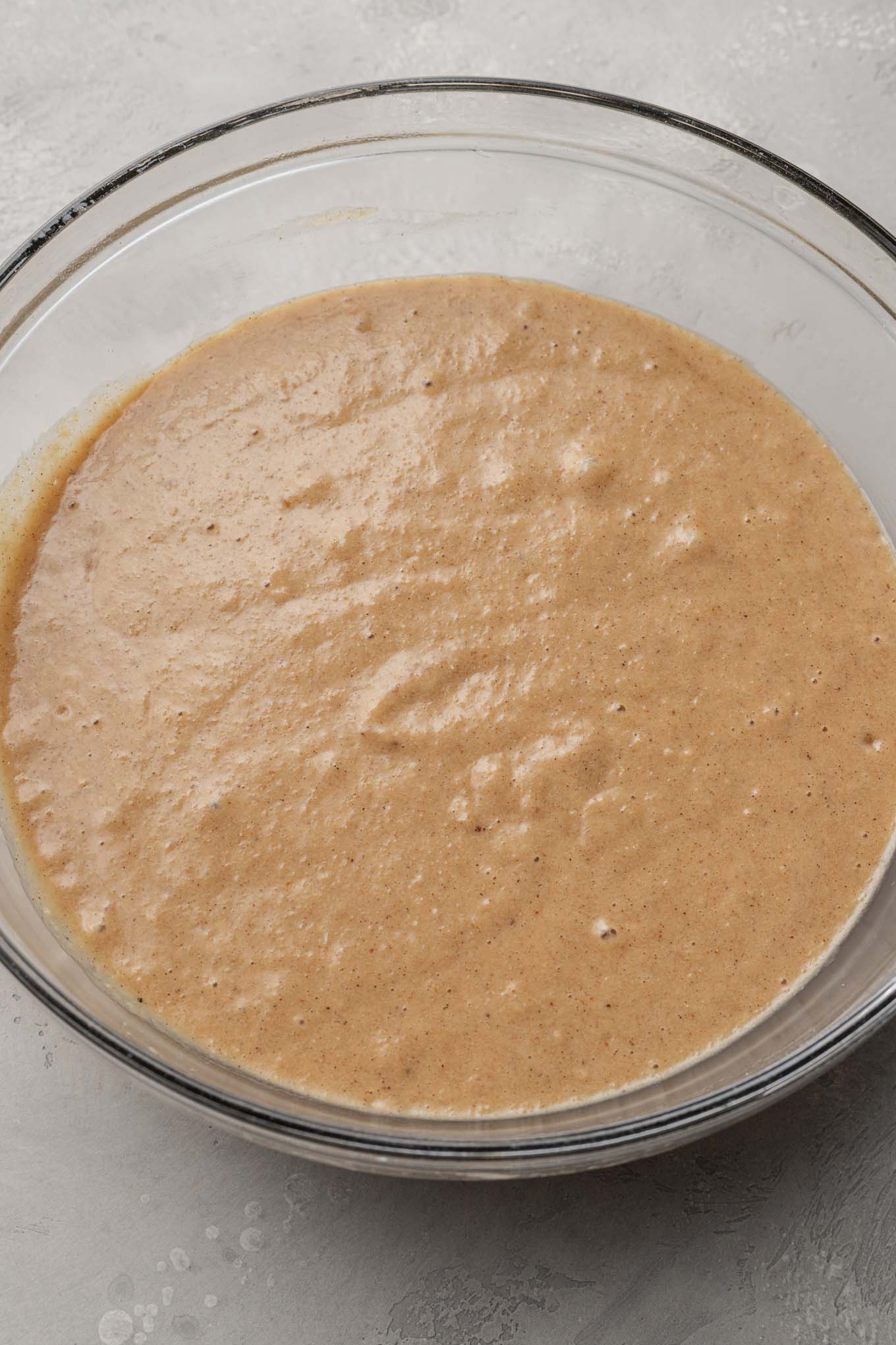 Una vista aérea de la masa de pastel de puré de manzana, en un tazón de vidrio. 