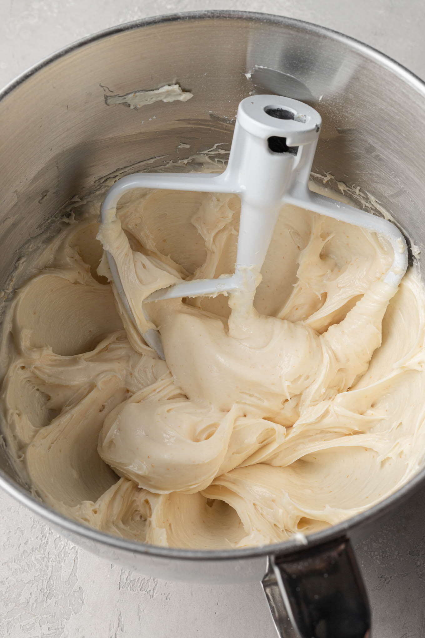 Dore el glaseado de queso crema y mantequilla en el tazón de una batidora de pie.