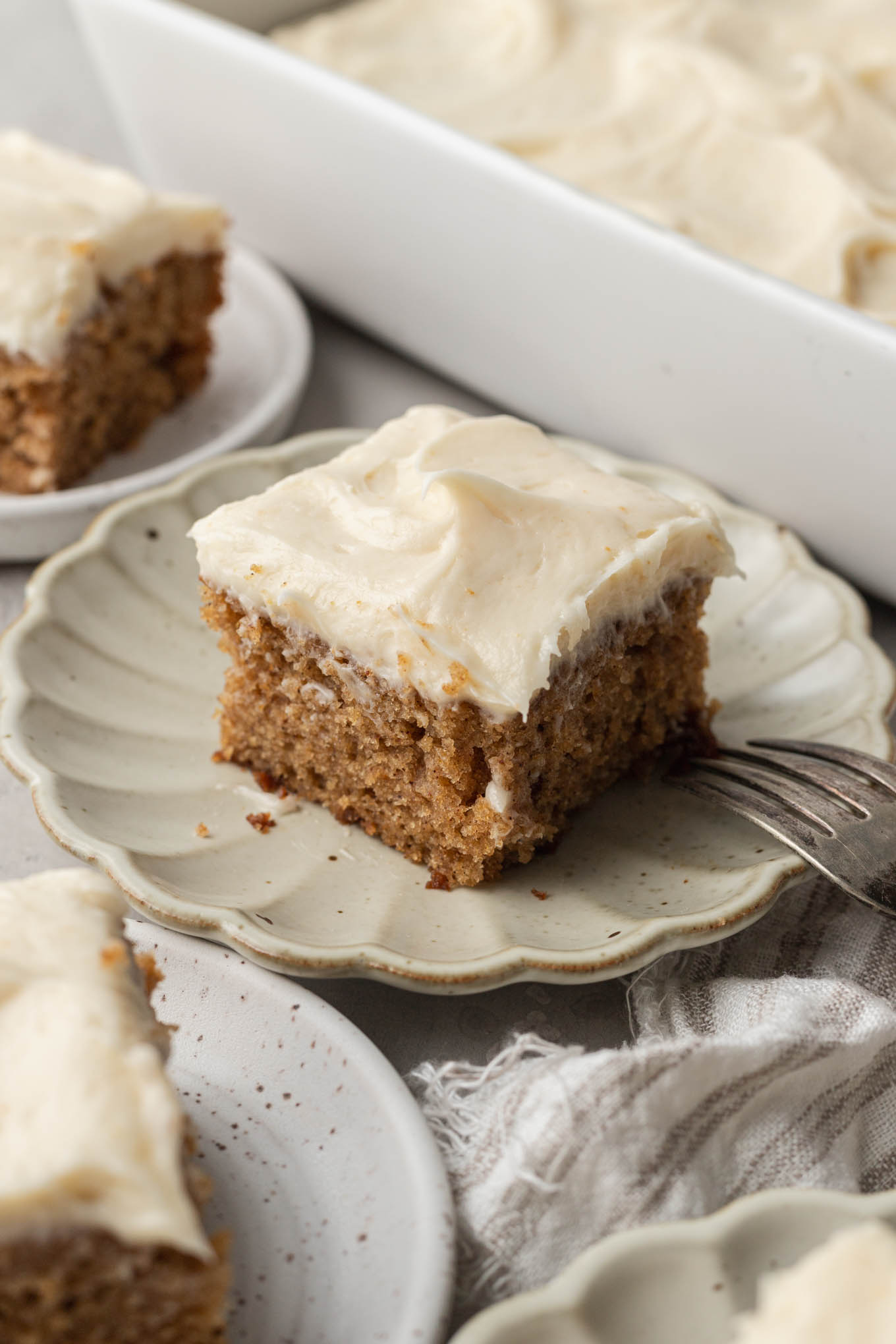 Un trozo de pastel de puré de manzana en un plato de postre de crema festoneada. 