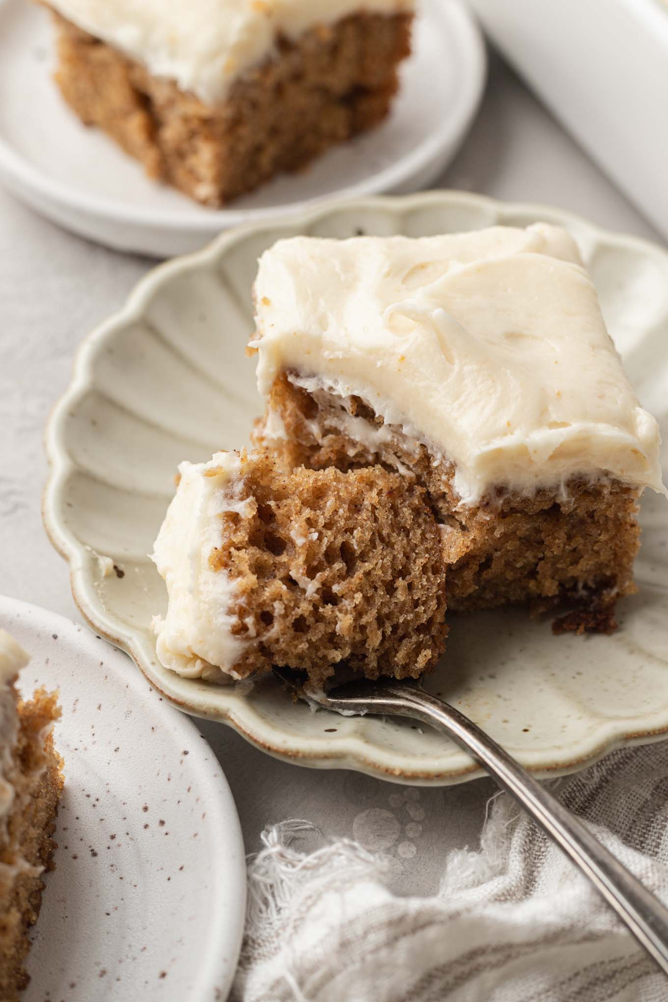 Un trozo de pastel de puré de manzana en un plato de postre festoneado.  Un bocado descansa sobre un tenedor. 