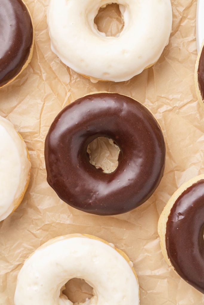 Una vista aérea de donas horneadas con glaseado sobre un trozo de papel pergamino. 