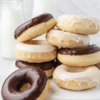 Varios donuts horneados apilados uno encima del otro. Los donuts están recubiertos de glaseado de chocolate y vainilla.