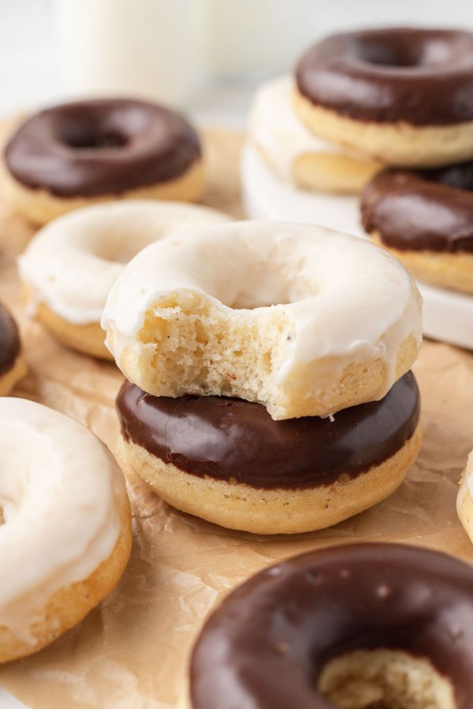 Donuts de pastel al horno sobre papel pergamino.  Dos donas están apiladas una encima de la otra en el centro. 
