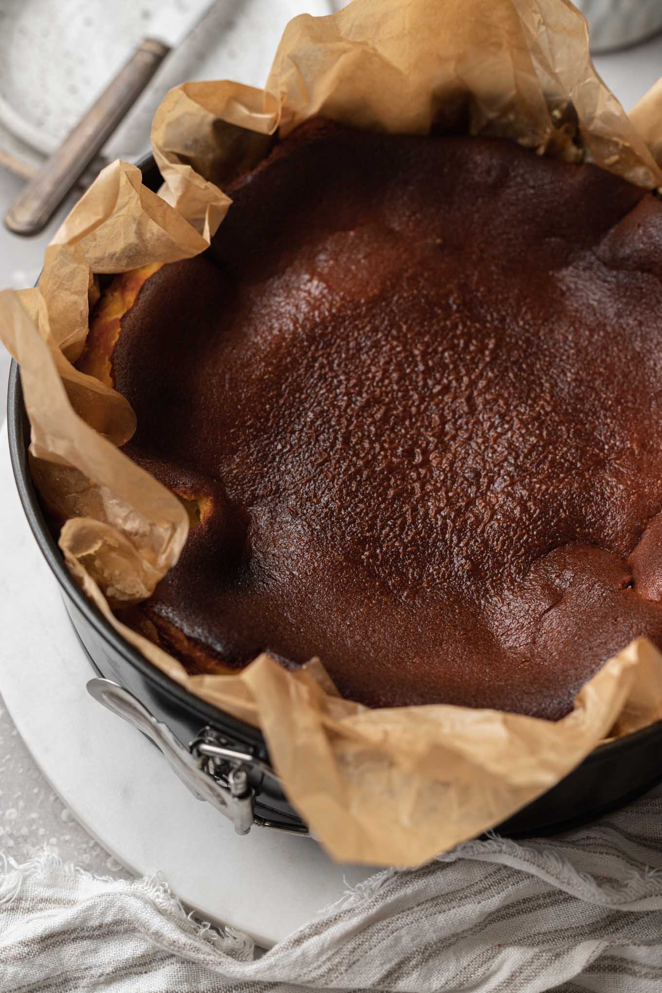 Una tarta de queso quemada en un molde desmontable forrado con papel pergamino. 