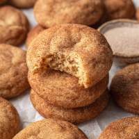 Tres snickerdoodles apilados uno encima del otro.  A la galleta superior le falta un bocado.