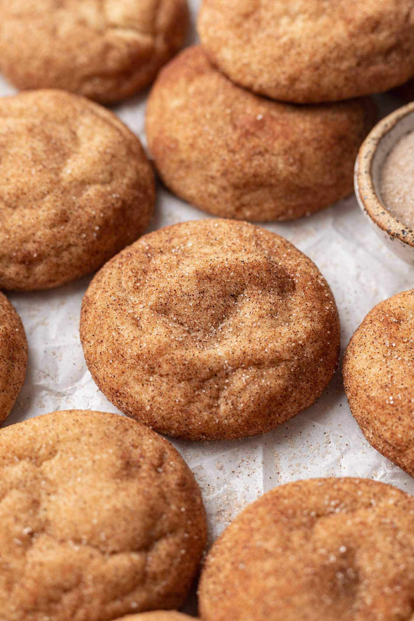 Una vista de cerca de snickerdoodles hechos con mantequilla marrón, sobre papel pergamino. 