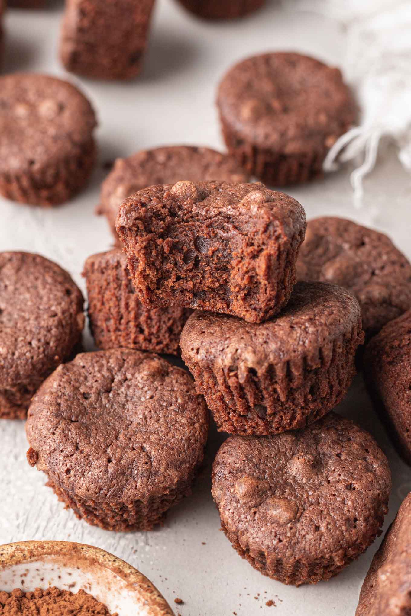 Un brownie del tamaño de un bocado al que le falta un bocado, descansando sobre una pila de brownies. 