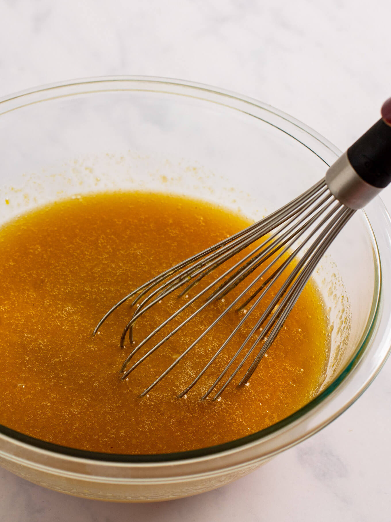 The wet ingredients for carrot cake whisked together in a glass mixing bowl.