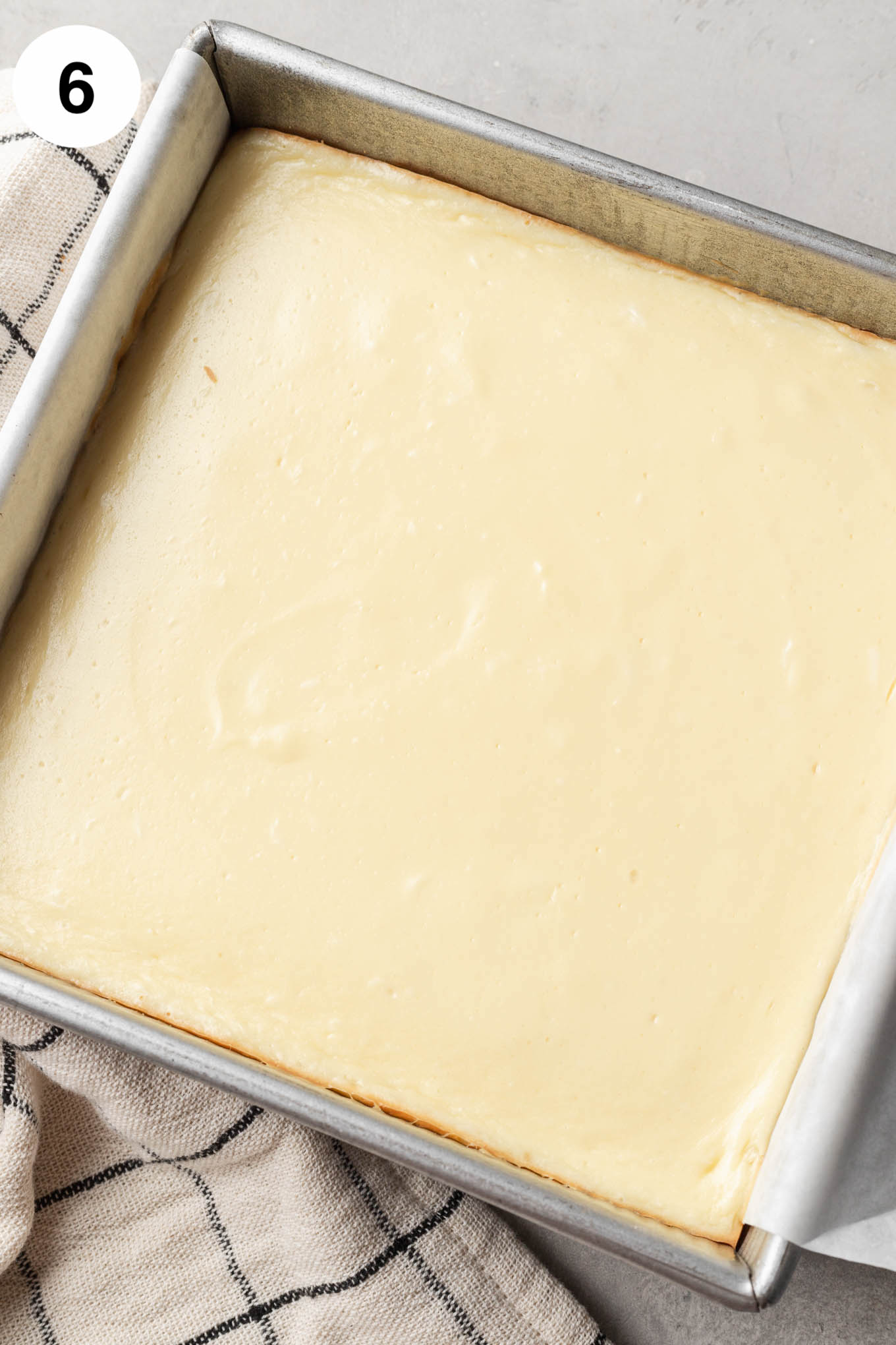 Una vista aérea de barras de tarta de queso horneadas en una fuente para hornear cuadrada. 