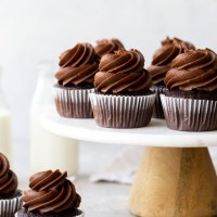 Varios cupcakes de chocolate encima de un soporte para tartas de mármol.