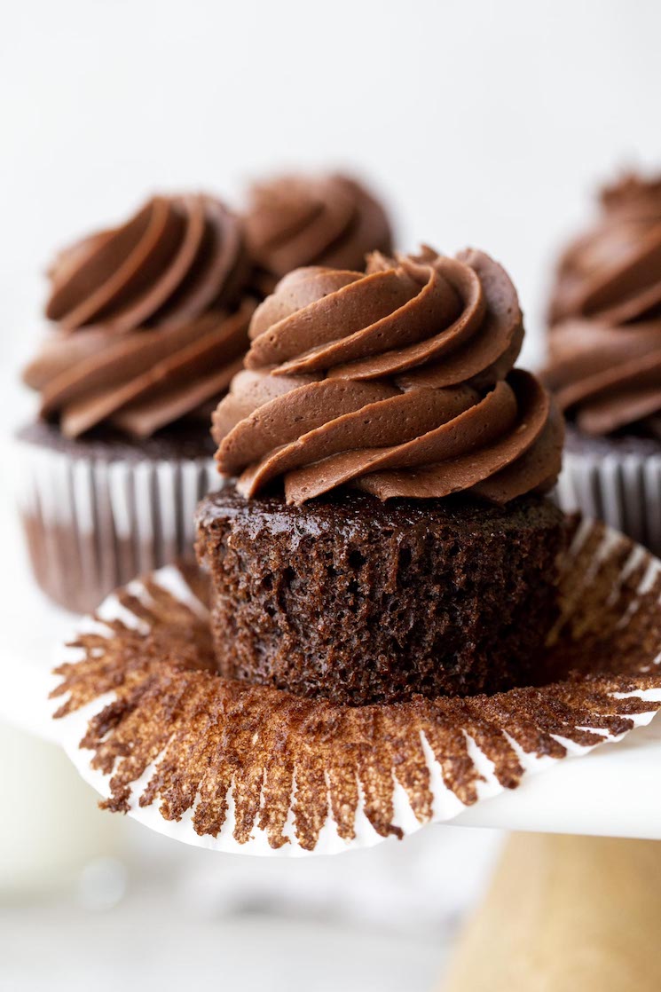 Un puesto de pasteles de mármol con cupcakes de chocolate cubiertos con glaseado de chocolate.