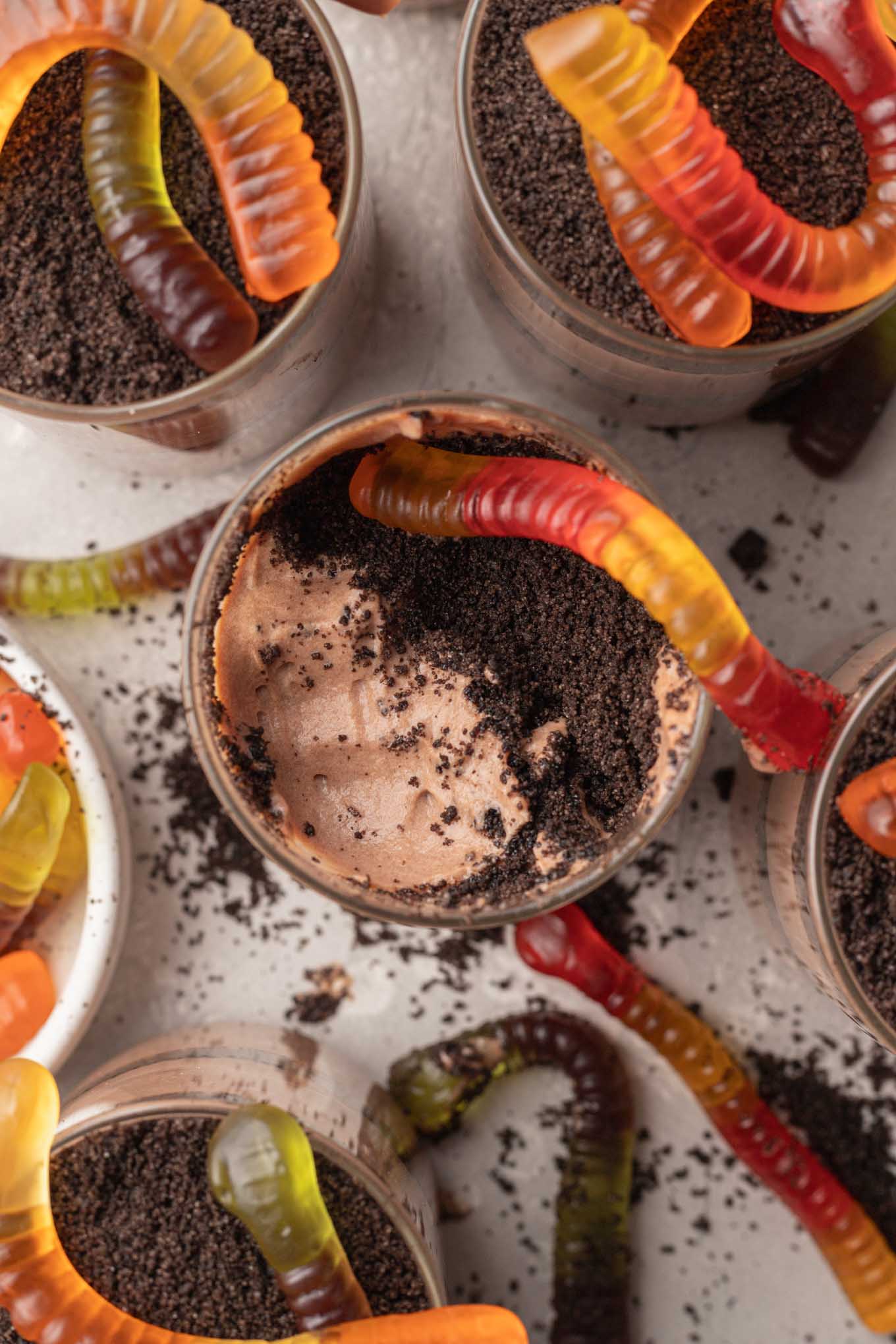 Una vista aérea de tazas de pudín de Oreo cubiertas con gusanos de goma. 