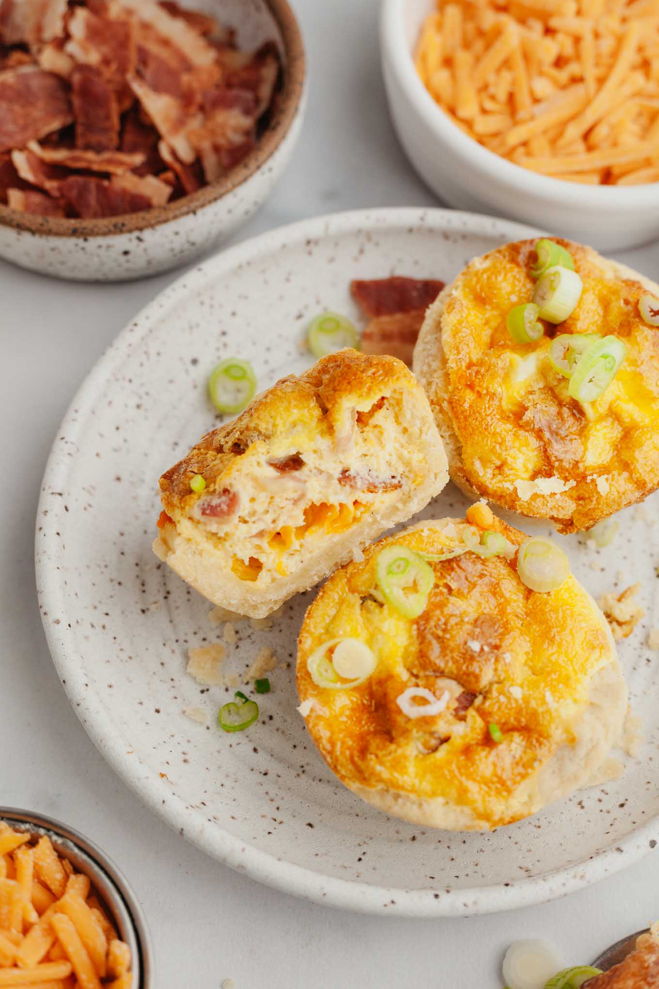 Una vista aérea de mini quiches en un plato.  Un quiche se ha cortado por la mitad. 