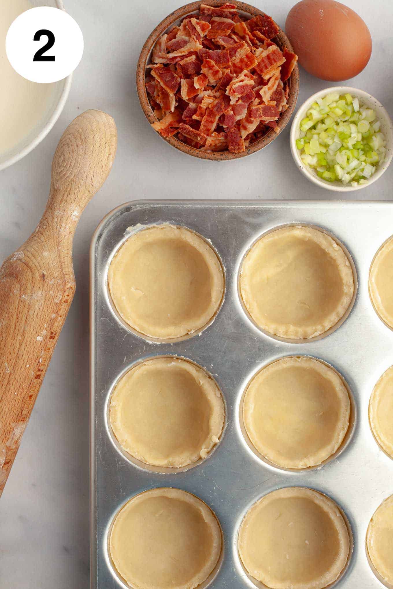 Una vista aérea de las masas de mini quiche prensadas en moldes para muffins. 