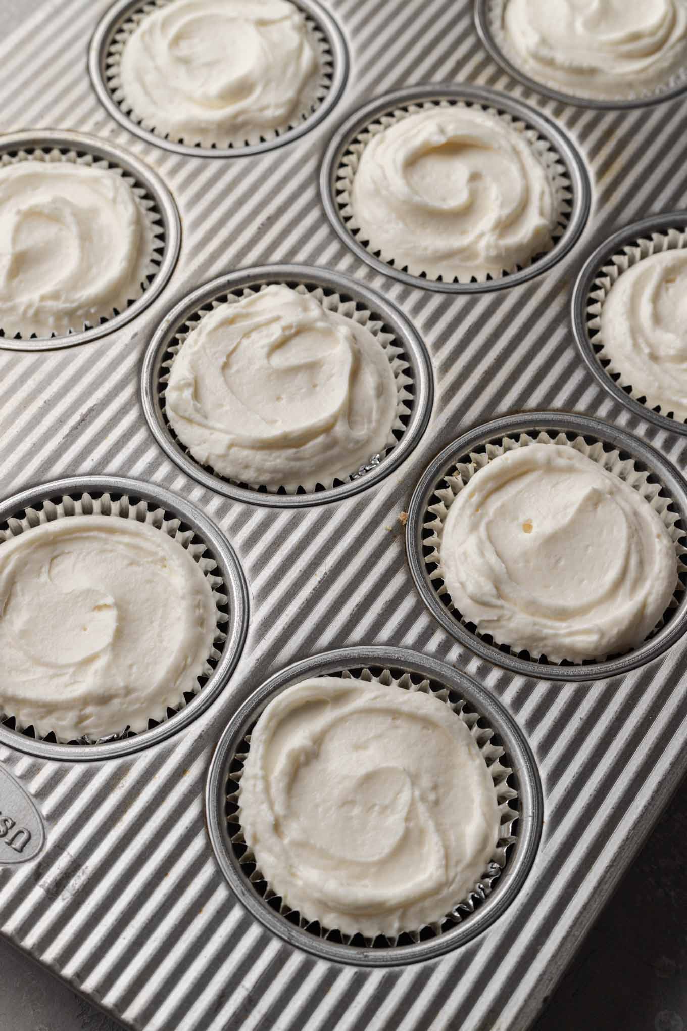 Una vista aérea de moldes para muffins llenos de relleno de tarta de queso. 