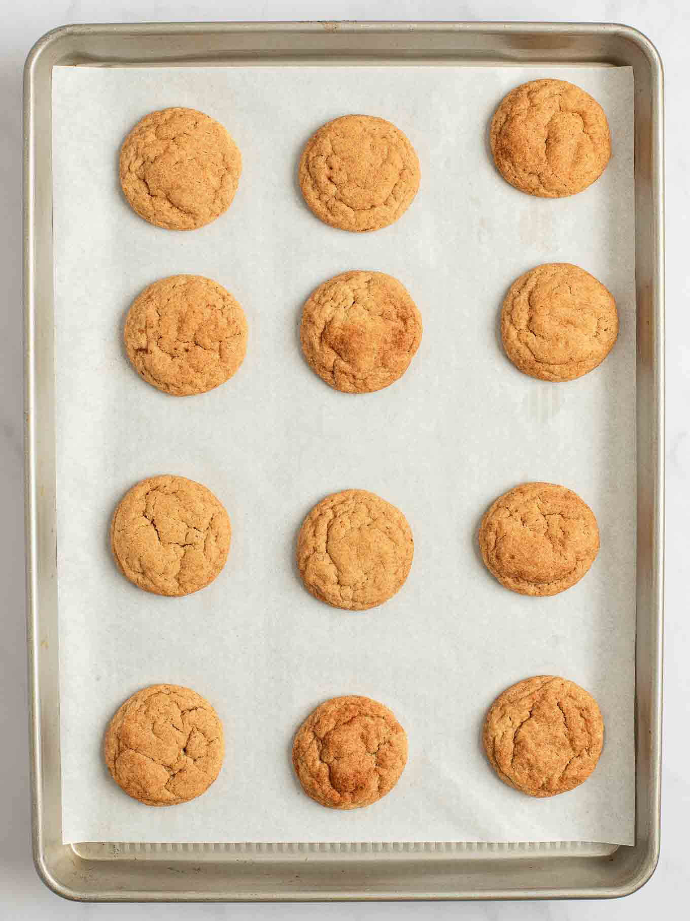 Una vista aérea de snickerdoodles de calabaza completamente horneados en una bandeja para hornear.