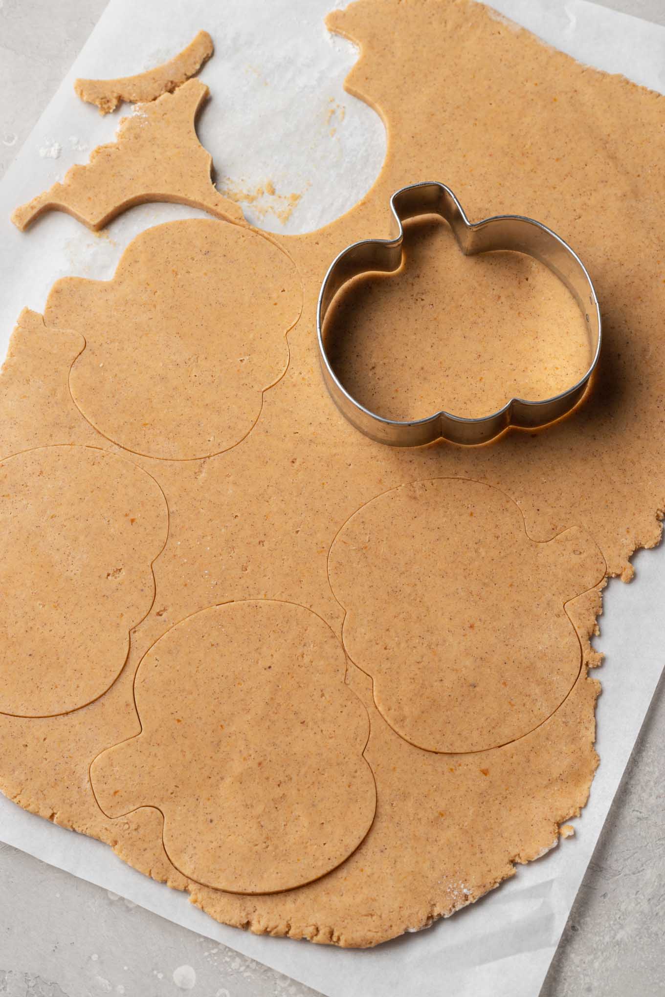 Una vista aérea de la masa de galletas de calabaza cortada en formas de calabaza.