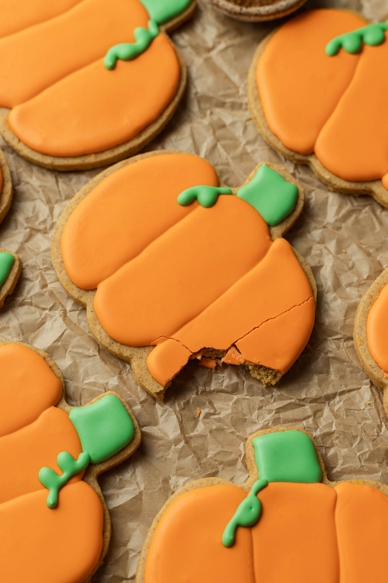 Una mirada de cerca a una galleta de azúcar con forma de calabaza a la que le falta un bocado. 