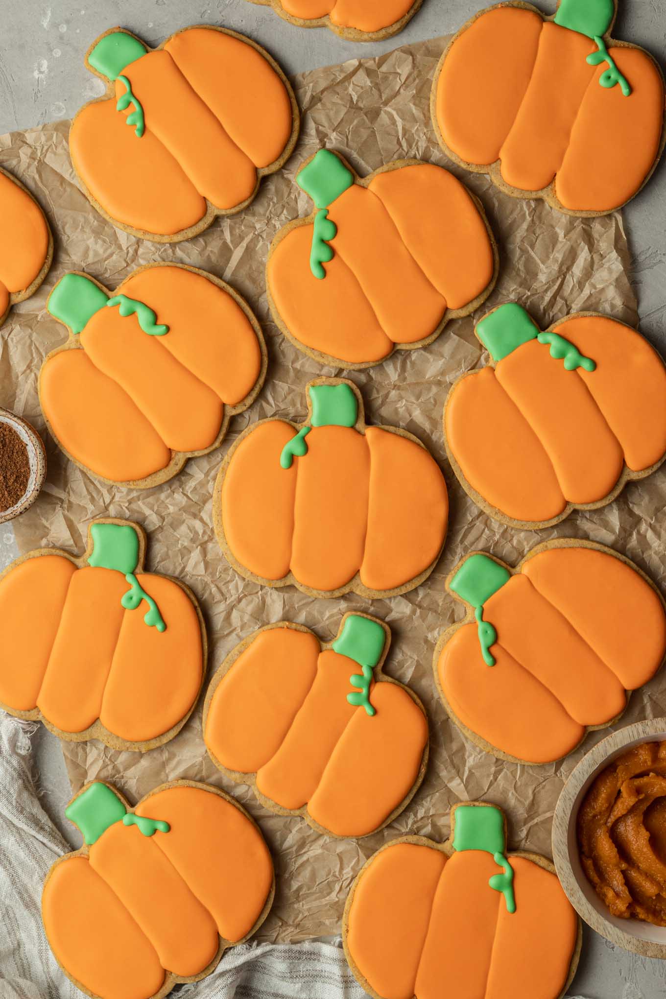 Una vista aérea de galletas de calabaza decoradas sobre papel pergamino. 