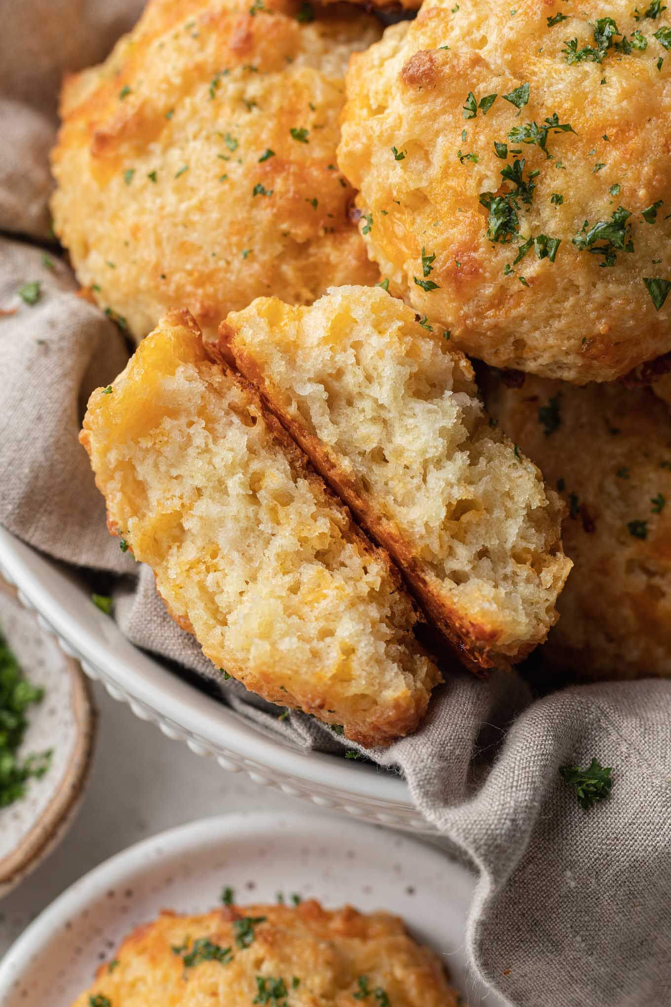 Una galleta Cheddar Bay partida por la mitad y volteada en una canasta de galletas. 