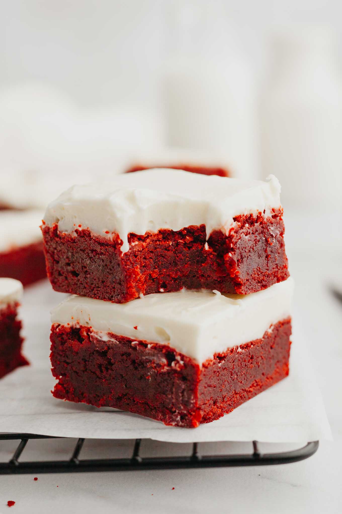 Dos brownies de terciopelo rojo apilados uno encima del otro;  al de arriba le falta un mordisco. 