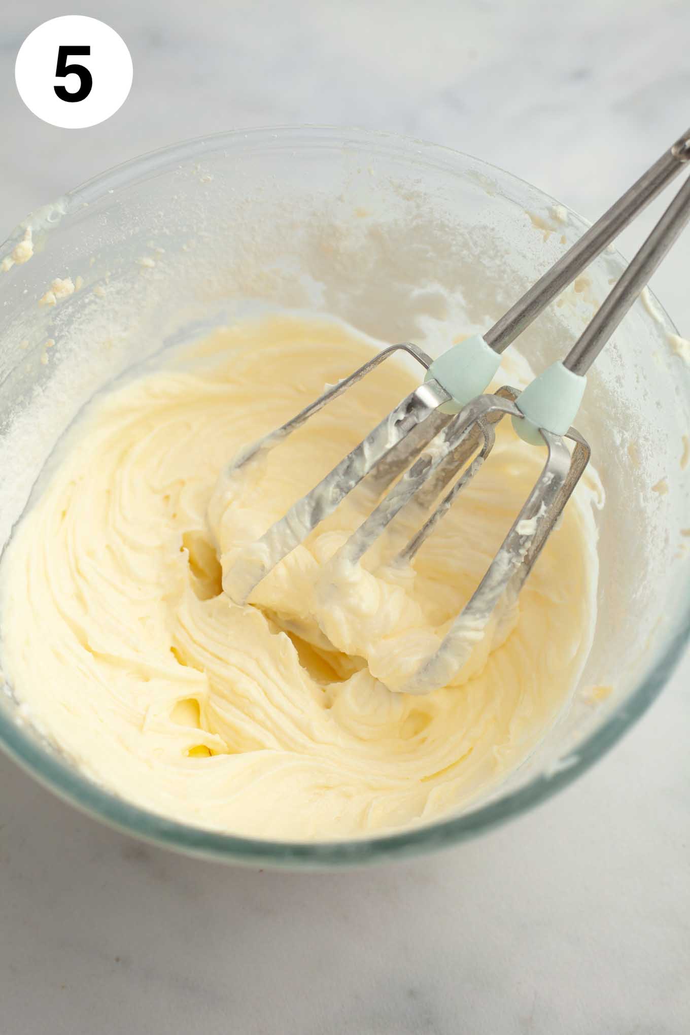 Glaseado de queso crema mezclado en un tazón de vidrio.