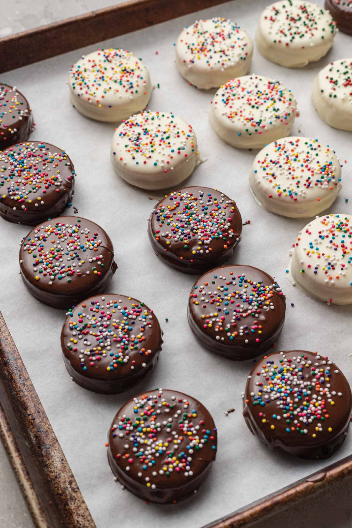 Un breve proceso que muestra filas de galletas saladas Ritz bañadas en chocolate en una bandeja para hornear. 