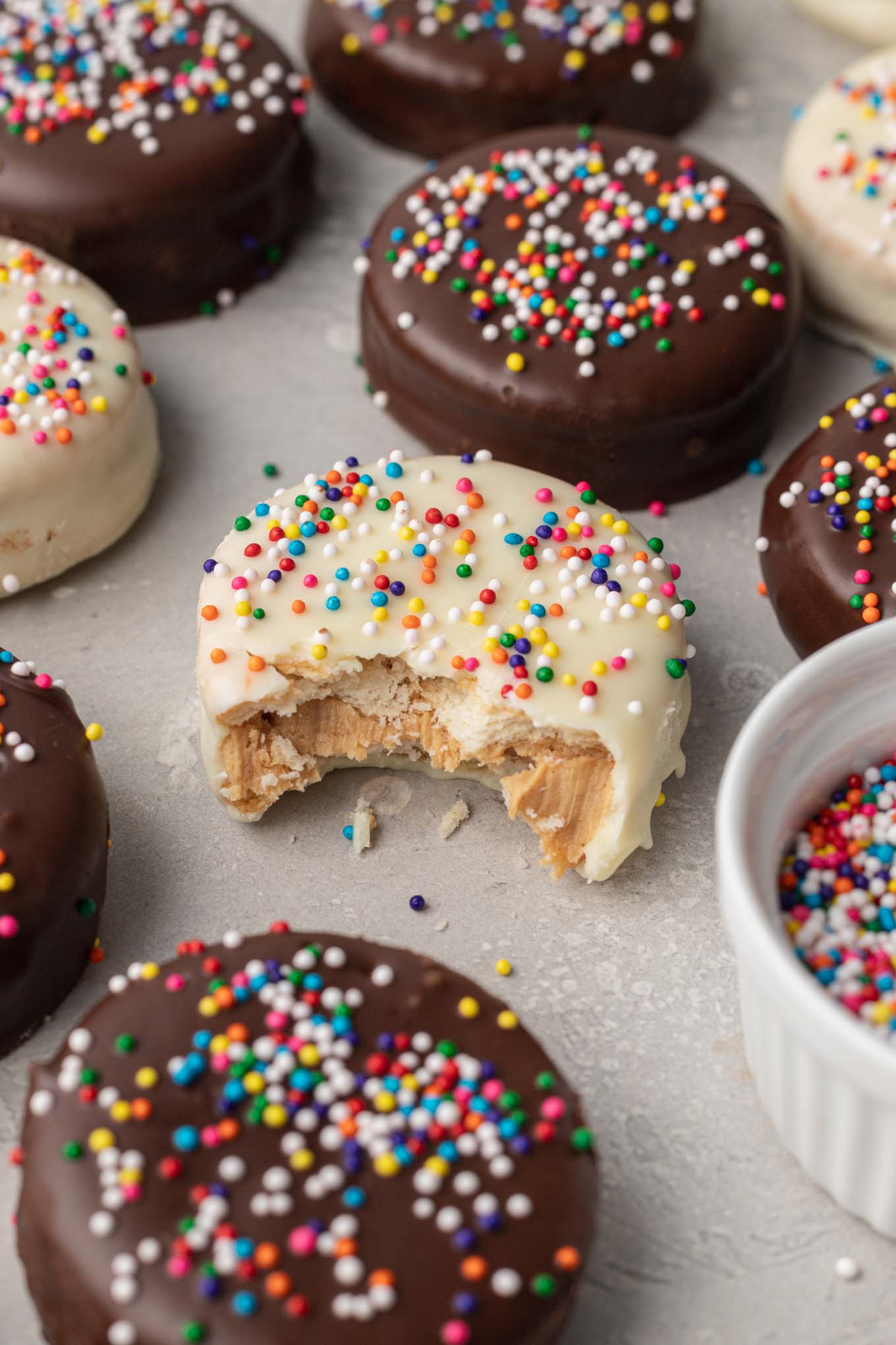 Una galleta Ritz cubierta de chocolate blanco a la que le falta un bocado.  La cookie está rodeada de aún más cookies. 