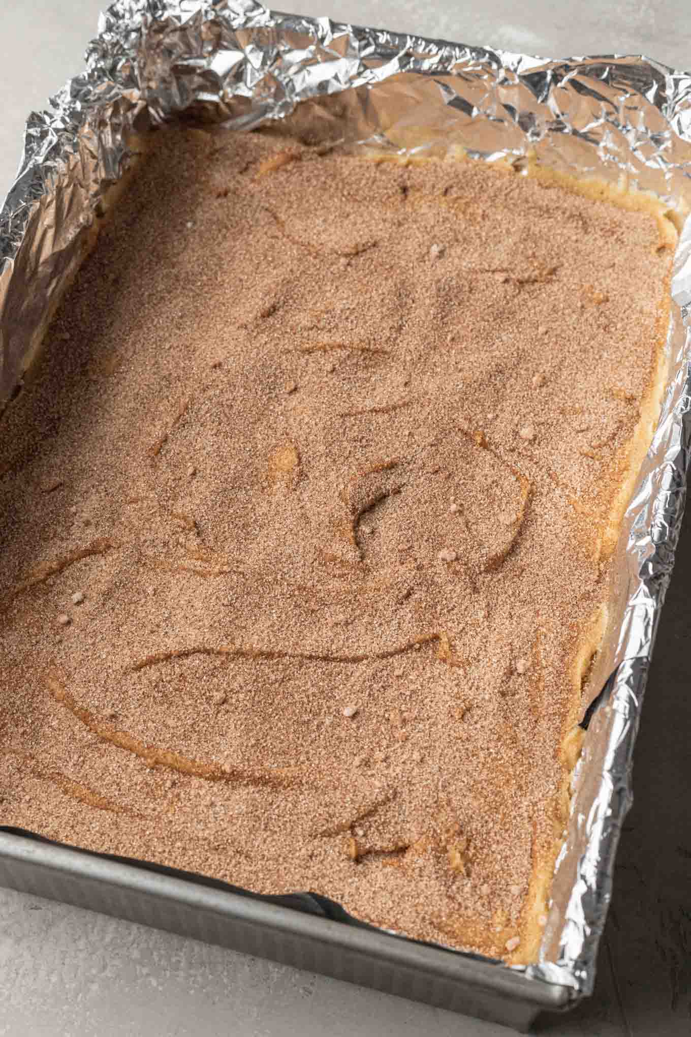 Azúcar y canela espolvoreada sobre la masa para galletas.