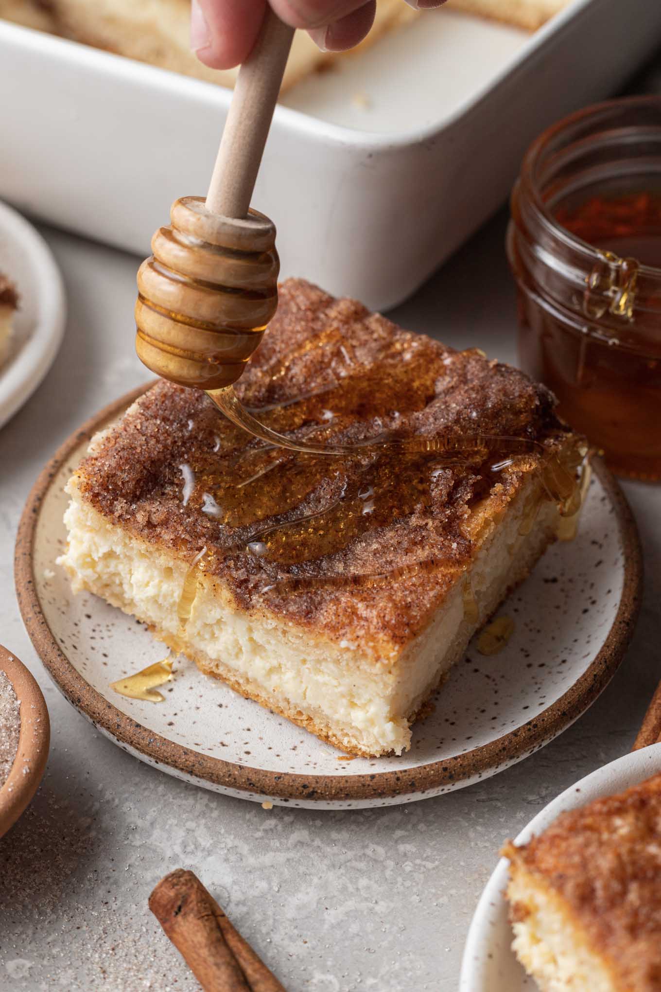 Una rebanada de tarta de queso sopapilla rociada con miel. 