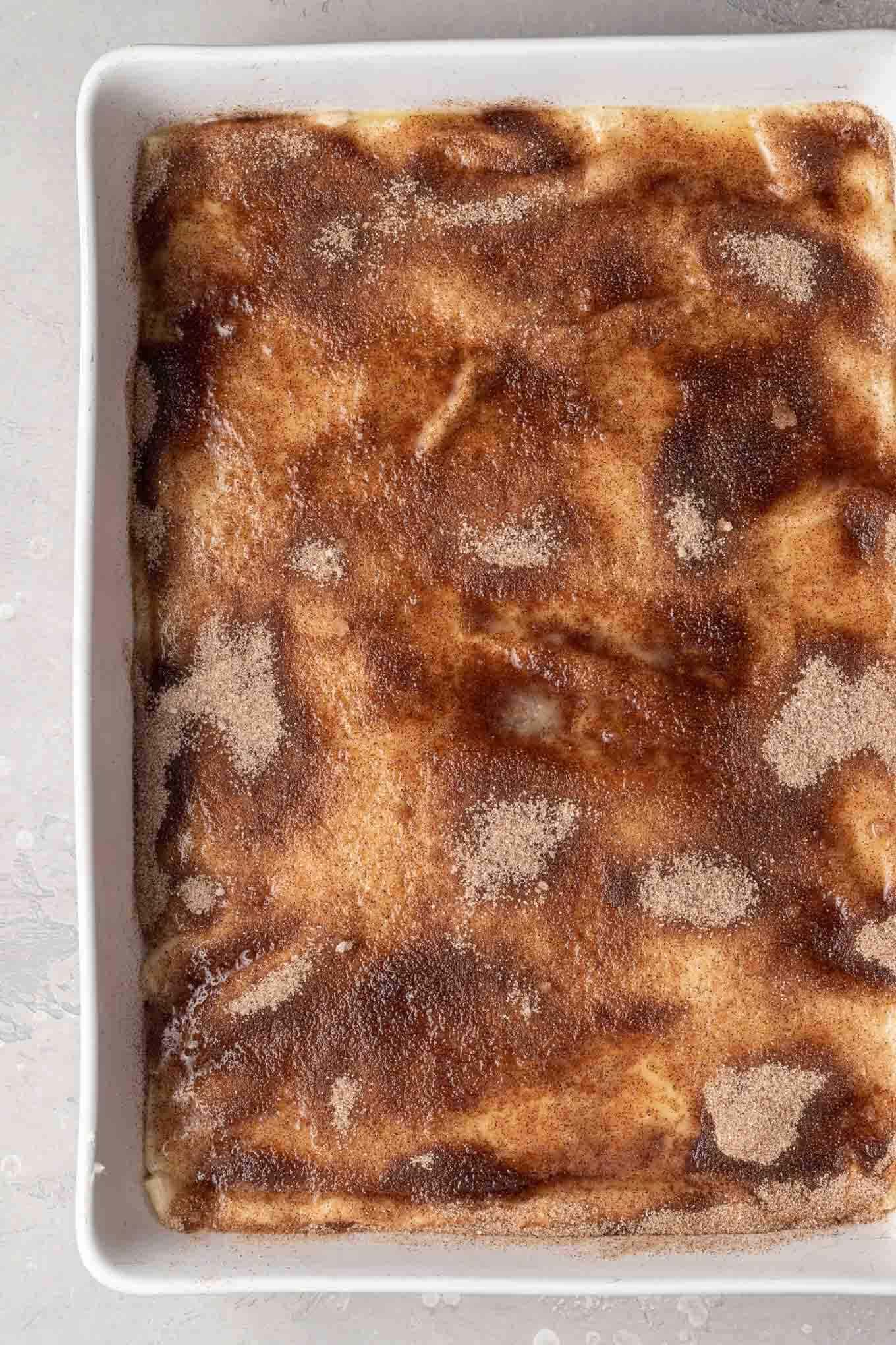 Una vista aérea de una tarta de queso tipo sopapilla cubierta con canela y azúcar, lista para hornear. 