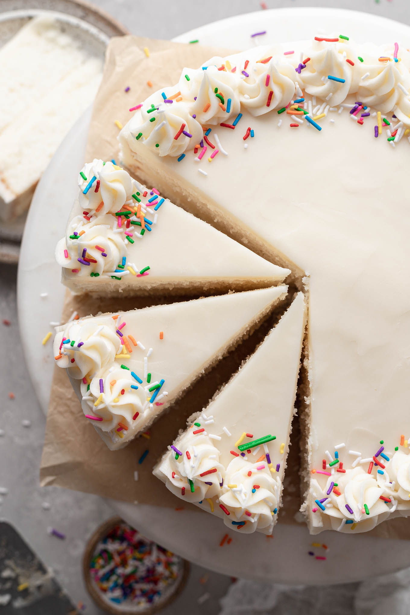 Una vista aérea de un pastel blanco casero en un puesto de pasteles. Se han cortado tres rodajas.