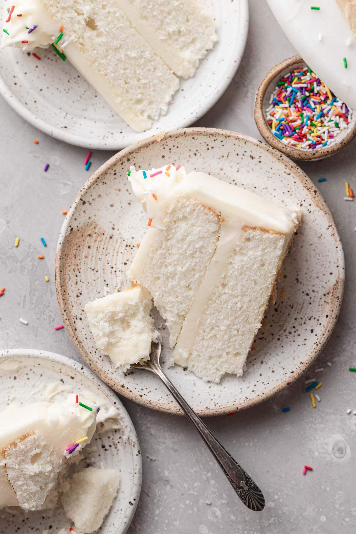 Una vista aérea de tres rebanadas de pastel blanco en platos de postre.