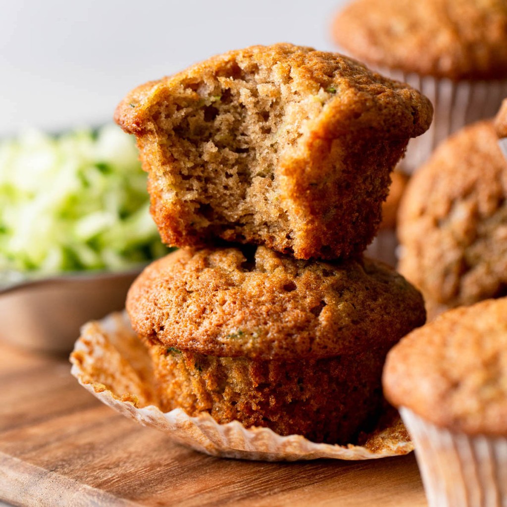 Dos muffins de pan de calabacín apilados uno encima del otro.  Al panecillo superior le falta un bocado. 